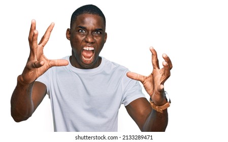 Young African American Man Wearing Casual White T Shirt Shouting Frustrated With Rage, Hands Trying To Strangle, Yelling Mad 