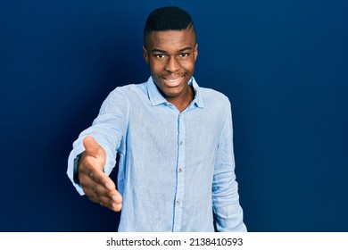 Young African American Man Wearing Casual Clothes Smiling Friendly Offering Handshake As Greeting And Welcoming. Successful Business. 