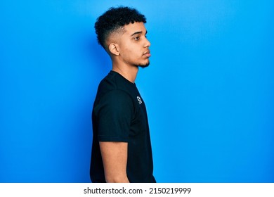 Young African American Man Wearing Staff T Shirt Looking To Side, Relax Profile Pose With Natural Face And Confident Smile. 