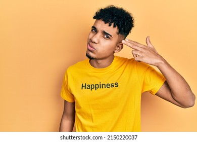 Young african american man wearing t shirt with happiness word message shooting and killing oneself pointing hand and fingers to head like gun, suicide gesture. 