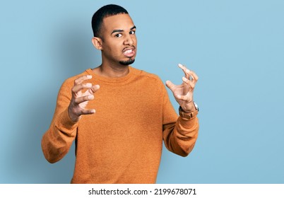 Young African American Man Wearing Casual Clothes Shouting Frustrated With Rage, Hands Trying To Strangle, Yelling Mad 