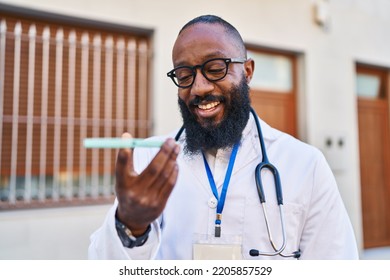 Young African American Man Wearing Doctor Uniform Using Smartphone At Hospital