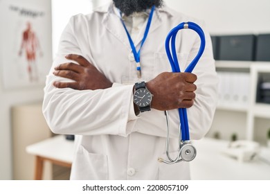 Young African American Man Wearing Doctor Uniform Standing With Arms Crossed Gesture At Clinic