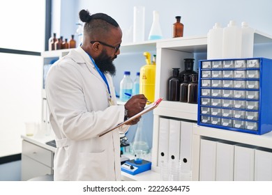 Young African American Man Wearing Scientist Uniform Writing On Clipboard At Laboratory