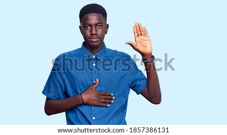 Young african american man wearing casual clothes swearing with hand on chest and open palm, making a loyalty promise oath 