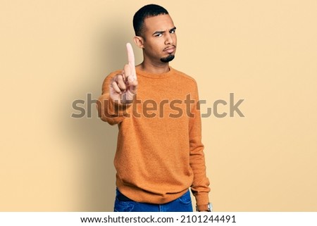 Young african american man wearing casual clothes pointing with finger up and angry expression, showing no gesture 