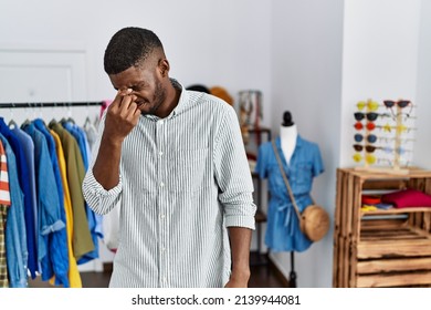 Young african american man working as manager at retail boutique tired rubbing nose and eyes feeling fatigue and headache. stress and frustration concept. 