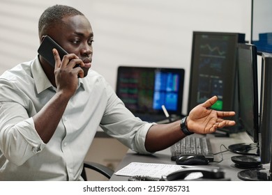 Young African American Man Working With Stock Trading Stats Having Phone Call With Dissatisfied Client