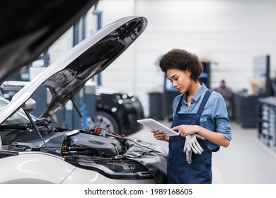 young african american mechanic holding digital tablet near car with open hood in auto repair service - Powered by Shutterstock