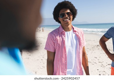 Young African American men enjoy a sunny beach day. Casual attire suggests a relaxed outdoor gathering among friends.