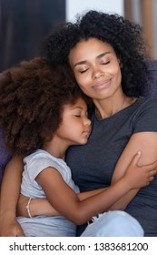 Young African American Mommy Relax On Couch Hugging Little Cute Daughter Falling Asleep Together, Loving Black Mom Cuddle With Small Kid, Caressing Folding To Breast, Have Close Tender Moment