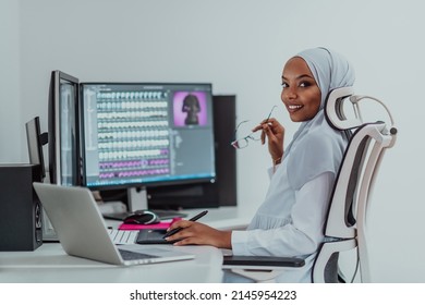 Young African American Muslim businesswoman in smart casual wear discussing business and smiling while sitting in the creative coworking startup creative startup office with dual screen. - Powered by Shutterstock