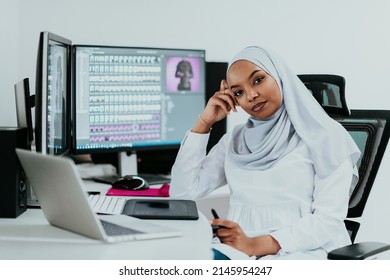 Young African American Muslim businesswoman in smart casual wear discussing business and smiling while sitting in the creative coworking startup creative startup office with dual screen. - Powered by Shutterstock