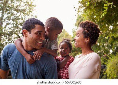 Young African American parents carrying children in garden