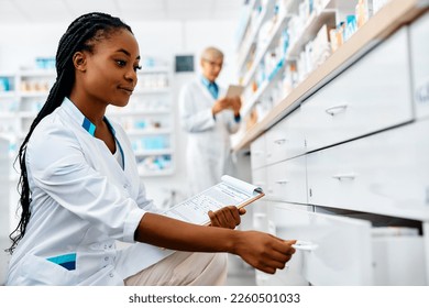 Young African American pharmacist checking medicine supplies while working in a pharmacy. Copy space.  - Powered by Shutterstock