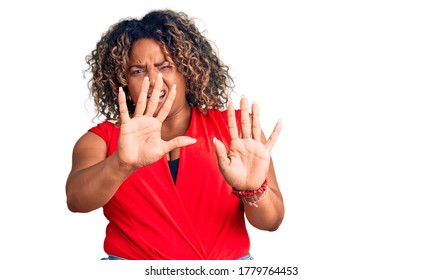 Young african american plus size woman wearing casual style with sleeveless shirt afraid and terrified with fear expression stop gesture with hands, shouting in shock. panic concept. 
