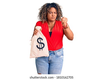 Young African American Plus Size Woman Holding Money Bag With Dollar Symbol Annoyed And Frustrated Shouting With Anger, Yelling Crazy With Anger And Hand Raised 