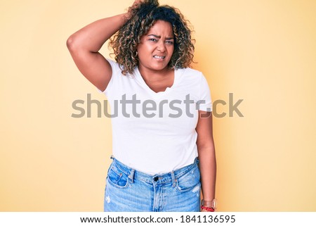 Young african american plus size woman wearing casual white tshirt confuse and wonder about question. uncertain with doubt, thinking with hand on head. pensive concept. 