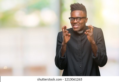 Young african american priest man over isolated background smiling crossing fingers with hope and eyes closed. Luck and superstitious concept. - Shutterstock ID 1213061263