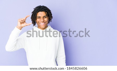 Young african american rasta man holding something little with forefingers, smiling and confident.
