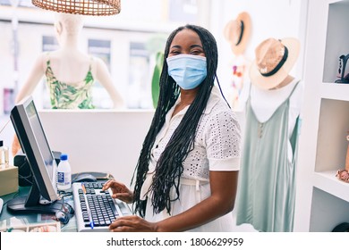 Young African American Shopkeeper Woman Wearing Medical Mask Working At Clothing Store