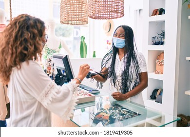 Young African American Shopkeeper Woman Wearing Medical Mask Working At Clothing Store