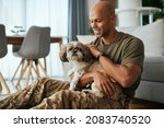 Young African American soldier cuddling his dog while spending time together at home.