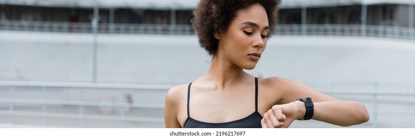 Young African American Sportswoman Looking At Smart Watch On Stadium, Banner