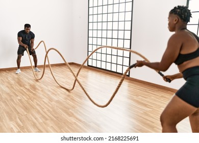Young African American Sporty Couple Training With Battle Rope At Sport Center.