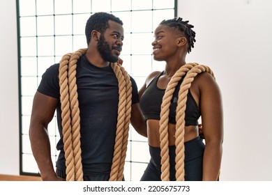 Young African American Sporty Couple Smiling Happy Holding Battle Rope At Sport Center.