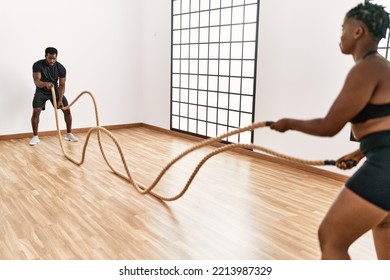 Young African American Sporty Couple Training With Battle Rope At Sport Center.