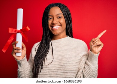 Young African American Student Girl Holding University Diploma Over Red Isolated Background Very Happy Pointing With Hand And Finger To The Side