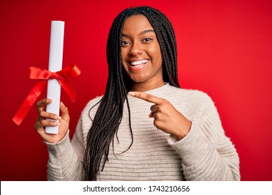 Young African American Student Girl Holding University Diploma Over Red Isolated Background Very Happy Pointing With Hand And Finger