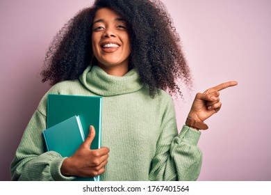 Young African American Student Woman With Afro Hair Reading Books Over Pink Background Very Happy Pointing With Hand And Finger To The Side