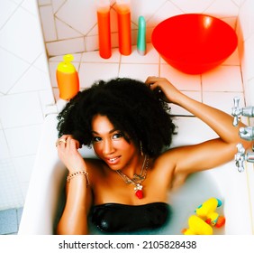 young african american teen girl laying in bath with foam, wearing swag jewelry flawless, making selfie