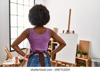 Young african american woman and afro hair at art studio standing backwards looking away and arms body 