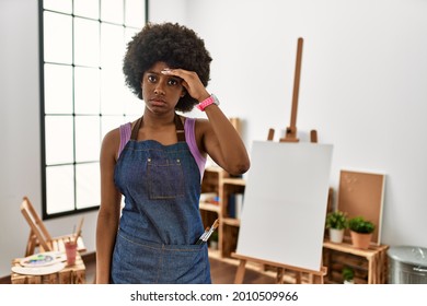 Young african american woman with afro hair at art studio worried and stressed about a problem with hand on forehead, nervous and anxious for crisis 