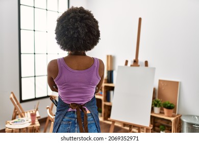 Young african american woman and afro hair at art studio standing backwards looking away and crossed arms 