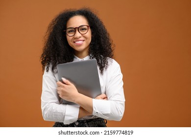 Young African American Woman With Afro Hairstyle Wearing Smart Casual Wear And Stylish Eyeglasses Standing Isolated On Brown , Carrying Laptop Computer, Smiling, Female Office Employee, Student