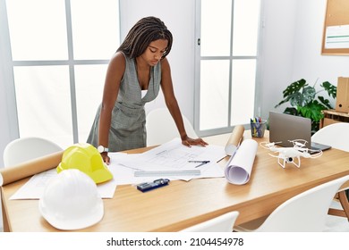 Young african american woman architect looking house plans at architecture studio - Powered by Shutterstock