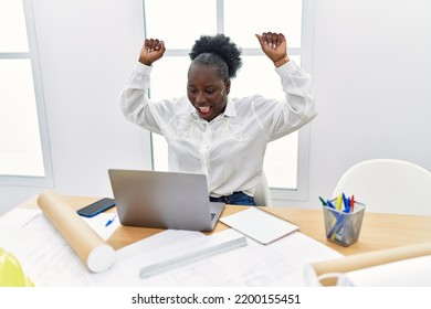 Young African American Woman Architect Using Laptop With Fists Raised Up At Architecture Studio