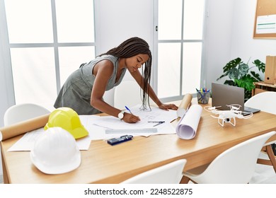 Young african american woman architect writing on house plans at architecture studio - Shutterstock ID 2248522875