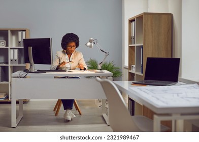 Young african american woman auditor checking financial documents with magnifying glass over office desk. Fraud investigation and tax audit. Accountant searching information in document. - Powered by Shutterstock