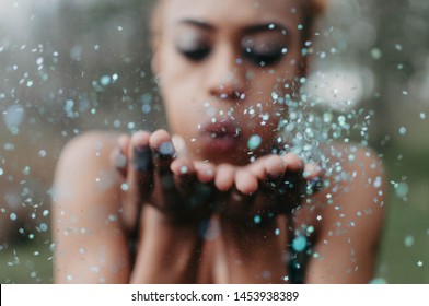 A Young African American Woman Blowing Glitter Confetti