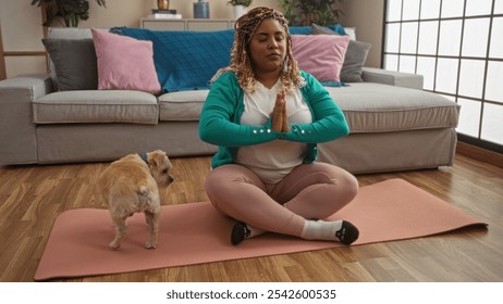 Young african american woman with braids meditating on a yoga mat in a cozy living room along with her small dog. - Powered by Shutterstock