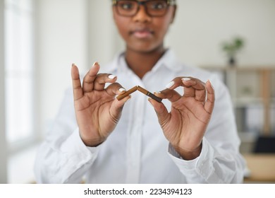 Young African American woman breaks cigarette as she promotes quitting harmful addictive habit during public campaign on World No Tobacco Day. Close up broken cigarette in hands. Stop Smoking concept - Powered by Shutterstock