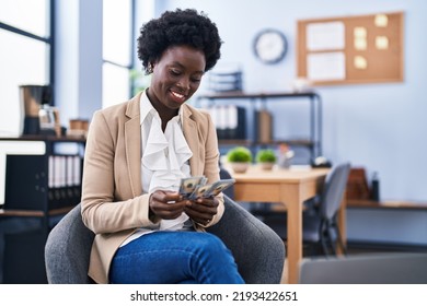 Young african american woman business worker counting dollars sitting on chair at office