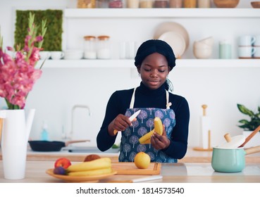 young african american woman is chopping fruits at the modern kitchen - Powered by Shutterstock