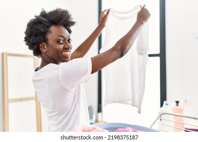 Young african american woman doing laundry looking clothes at laundry - Powered by Shutterstock