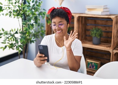 Young african american woman doing video call with smartphone looking positive and happy standing and smiling with a confident smile showing teeth  - Shutterstock ID 2230588691